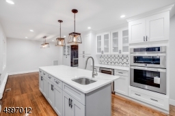 Beautiful wood cabinetry, quartz counter tops & center island with a breakfast bar, butler's pantry and a 24" wine cooler