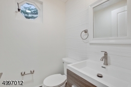 First floor powder room with new floor porcelain tile, ceramic wall tile, and wood vanity.