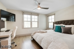 En-suite Guest Bedroom / Home Office featuring hardwood floors, deep baseboard moldings, two exposures of windows, double closet