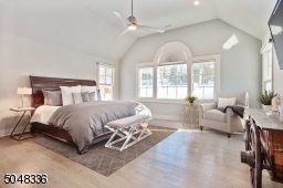 Primary Bedroom features double paneled privacy doors, triple palladium window, vaulted ceiling, hardwood floors, deep baseboard molding, ceiling fan, recessed lights and dressing area with 3 custom fitted closets (2 large walk-ins plus a lines closet)