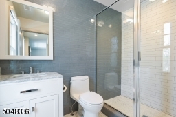 En-suite Bathroom features grey and white marble floor, walk-in glass enclosed shower with white and grey subway tile and vanity with grey marble top