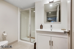 Full Bathroom featuring stone flooring, white vanity with white marble top, glass enclosed walk-in shower with subway tile