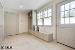 Mud Room featuring stone floor, built-in cubbies with under storage and bench, access to rear yard, walk-in coat closet / pantry and direct access to attached garage