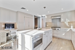 Features hardwood floors, deep baseboard moldings, granite counters, built-in speakers,double sliders to rear patio, custom light grey cabinetry, large island w/seating for 4, grey tile backsplash,recessed lights,under cabinet lights,high-end appliances