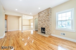 living room with new hardwood floors recessed lighting and allows access to 2nd floor stairs, sunken family room, and to the kitchen. Functioning fireplace.