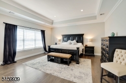 Primary Bedroom Suite with hardwood floors, tray ceiling with recessed lights, a triple window and a large walk-in closet