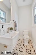 Check out this stylish powder bath featuring marble cafe hex tile finished with brass and black fixtures.  Look for the door marked WC on your way into the family room.