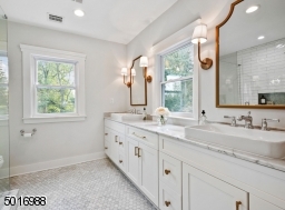 Enjoy the luxury of a marble bath with a 10ft long double vanity with marble countertops, oversized sinks, lots of natural light, a walk-in shower, custom shower glass, a large linen cabinet and Kohler plumbing fixtures.  Designed by Clear Space Home.