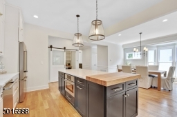 This spacious open concept kitchen and dining room was designed by Clear Space Home with marble-look quartz, Thermador appliances, custom white oak details, double farm sink, subway backsplash and satin brass hardware.