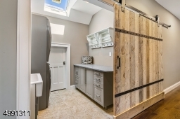 Located on Level 2, an impressive reclaimed wood barn door slides open to this light-filled space. Kenmore Elite washer and dryer, utility sink, cabinetry, soapstone counter top, expandable drying racks.
