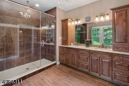 Wood custom vanity, marble counter top, mounted hutches. Oversize glass-enclosed shower. Plumbed for future soaking tub. Stone flooring.