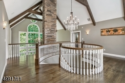 Swirled railing adds architectural interest in the loft as do the beamed volume ceiling and expansive windows.