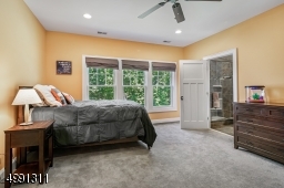 Spacious secondary bedroom with full bath, custom walk-in closet, attic access with pull-down stairs and hardwood flooring under plush wall to wall carpeting.