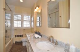 Features Carrera marble flooring and double vanity with a shower-over-tub