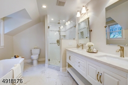 Luxury bath is goeorgeous and features a soaking tub, glass-enclosed large shower with decorative tiles and corner niches.