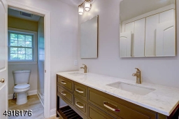 The main bath on this level has a tiled floor; deep, built-in cubby "linen" space; attractive double wood vanity with quartz countertop.
