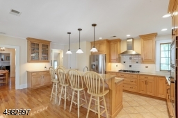 Large renovated kitchen boasts wood cabinets, center island, stainless steel appliances, wood floors with french door that leads to the deck