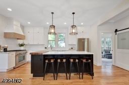 Chefs kitchen features an 8ft center island, 36in Thermador range, SS appliances, quartz countertops, double farm sink, custom range hood, custom butcherblock, drawer organizers, walk-in pantry with barn door, bar sink and wine fridge