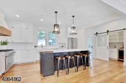 Chefs kitchen features an 8ft center island, 36in Thermador range, SS appliances, quartz countertops, double farm sink, custom range hood, custom butcherblock, drawer organizers, walk-in pantry with barn door, bar sink and wine fridge