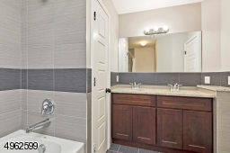 Double vanity, tub/shower with custom tiles and linen closet.