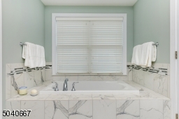 Luxurious ensuite bath with soaking tub, stall shower with frameless glass door, double sink vanity & tile floor