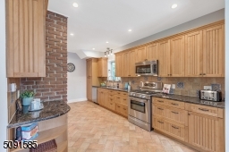 Chefs kitchen with stainless steel appliances and wood cabinetry.