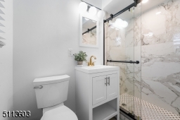 Primary bath has gorgeous quartz shower with frameless glass door with black hardware.