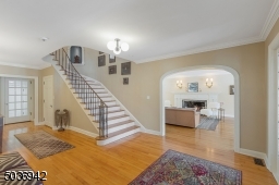 Wood floors & elegant staircase with metal railing & balusters