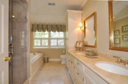Marble topped vanity and floors, spa tub and frameless shower