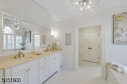 Primary Bathroom w/ tile floors w/ radiant heat, vaulted tray ceiling, chandelier, oversized walk-in shower, w/ marble & glass tile surround, soaking tub, baseboard molding, recessed lighting, dual custom vanities dual designer sconces & built-in speaker