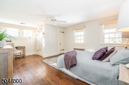 Spacious and freshly painted bedroom with ceiling fan, sconce lighting, desk area, 2 closets and full white bath with stall shower and large pedestal sink
