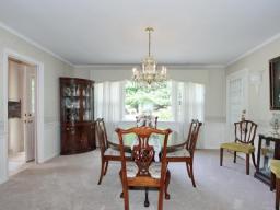 Large dining room with chair rail, chandelier and wall to wall carpeting over oak floors.