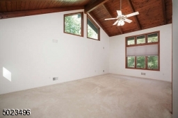 Comfortable room with high ceilings, a ceiling fan, double closets and windows on three walls.