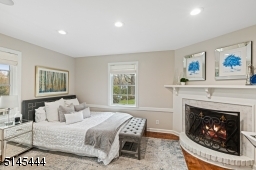 Bedroom / Home Office with parquet floors, corner wood burning fireplace with a round marble base, two exposures of windows, built-in open shelving, storage and a closet