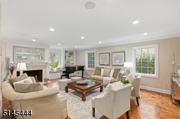 Living Room is an open concept to the Dining Room and  features hardwood floors, recessed lights, wood burning fireplace with stone surround and architectural display shelf, built-in shelving with storage and two exposures of windows