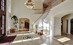 Sun drenched gracious Foyer with two story Mahogany door.