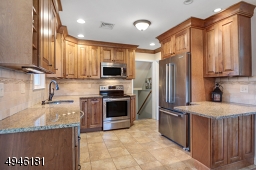 The kitchen boasts stainless steel appliances, granite countertops, tile backsplash, breakfast bar, wood cabinets & slow close drawers.