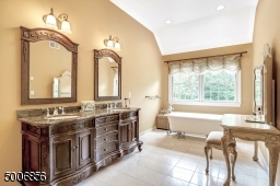 Master bath with custom cabinetry, heated flooring and a soaking tub and a stall shower.