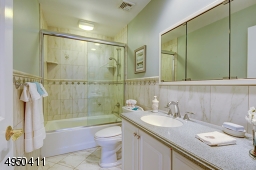 So pretty! - Porcelain floor, tiled glass enclosed shower-over-tub and custom wood vanity with Corian counter top.