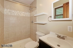 Updated 1st floor bath with herringbone accent tile, new commode,  vanity and laminated floor.