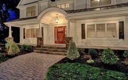 An  arched portico entry with wainscoting detail and a beautiful light fixture to light the way.
