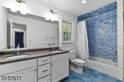 Full Hallway Bathroom with tile floors, wainscotting, white double vanity with granite top, recessed lights and two sconces