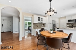 Chef?s Eat-In Kitchen with hardwood floors, crisp white custom cabinetry with glass display doors, granite counters, glass tiles backsplashes, built-in workspace, and high-end stainless steel appliances.