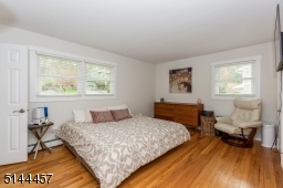Primary bedroom with ensuite bath with shower stall wood floors