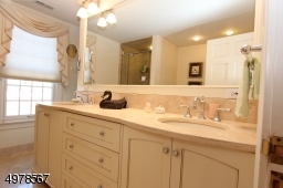 Tall twin sinks with marble vanity make getting ready easy.  Soothing cream and white colors enhance the spa feel.  Out of sight is a soaking tub and large tile shower stall.