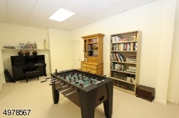 Another game section of the finished basement.  Tall ceilings perfect for home workout area and gym equipment needing headroom.  Door leads through workshop and out to parking lot.