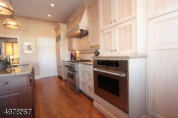 Cabinet doors hid storage and various appliances so this hardworking room takes on an uncluttered look.  Sub Zero fridge, Thermador 6 burner gas range with elec oven and powerful fan.  Addtl electric wall oven shown.  Pots and pans drawers