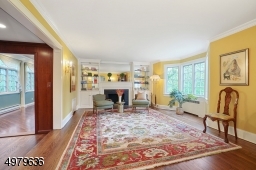 sun-lit living room with a wood burning fireplace, built-ins, hardwood floors
