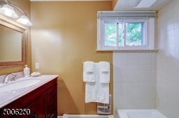 Recently remodeled features wood vanity, tiled floor and tiled shower-over-tub.