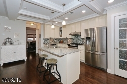 Features incl box beam ceiling, granite counters, tiled backsplash and stainless steel appliances. Kitchen island with gooseneck faucet in sink.